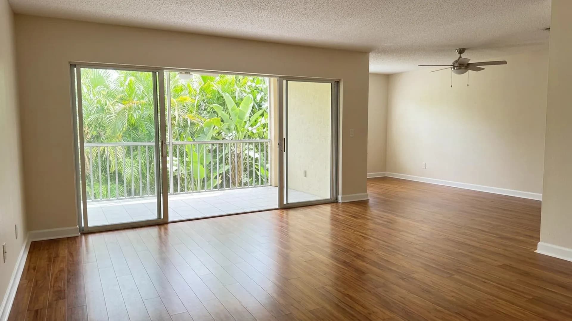 Empty Florida rental living room with clean hardwood floors, white baseboards and bright sliding glass doors ready for tenant turnover.